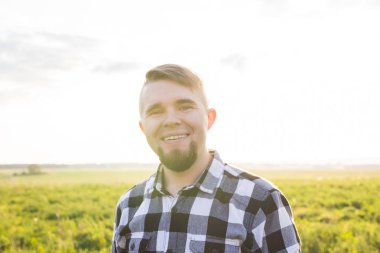 Kamera gülümseyen için seyir yakışıklı genç adam kırsal alan giyen gömlek, önünde
