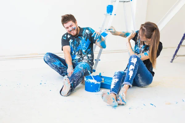 Concept de personnes, rénovation et intérieurs - Jeune couple assis sur le sol blanc et amusez-vous à la pause — Photo