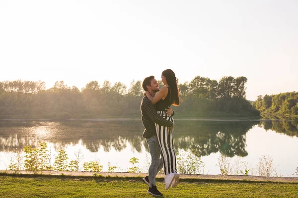 Pessoas, amor e conceito de natureza - Homem segurando mulher em seus braços sobre o fundo da natureza — Fotografia de Stock