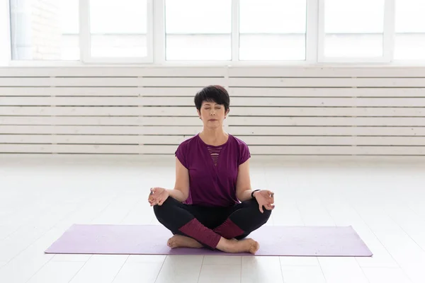 Yoga, harmony, people concept - Middle aged woman sitting in lotus position