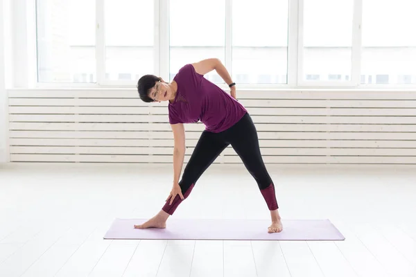 Yoga, concepto de personas - una mujer de mediana edad haciendo un yoga en el gimnasio —  Fotos de Stock