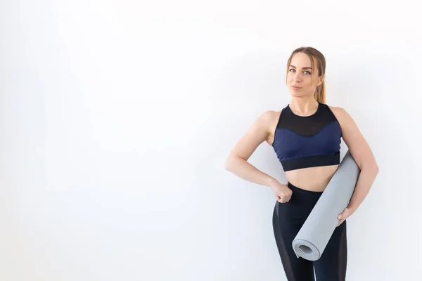 Concepto de personas, fitness y deporte - Mujer atractiva y saludable sosteniendo alfombra gris sobre fondo blanco con espacio para copiar —  Fotos de Stock