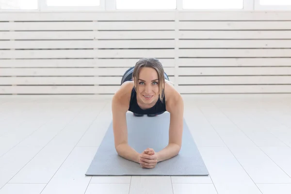Concepto de deporte, yoga y personas: una mujer joven está haciendo una tabla, tomando un equilibrio — Foto de Stock