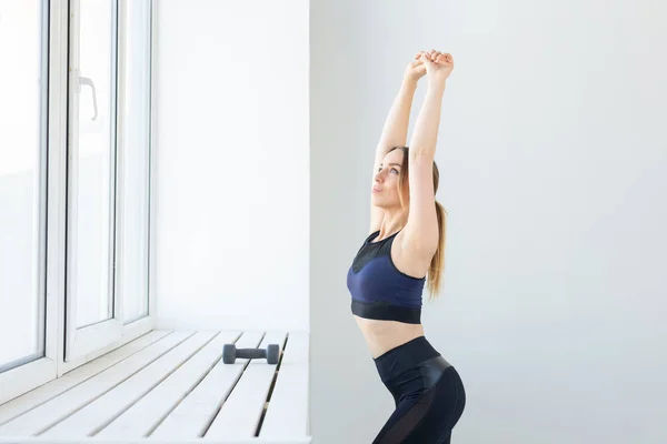 Gente, deporte y fitness concepto - mujer joven haciendo ejercicios que se extienden cerca de la ventana —  Fotos de Stock