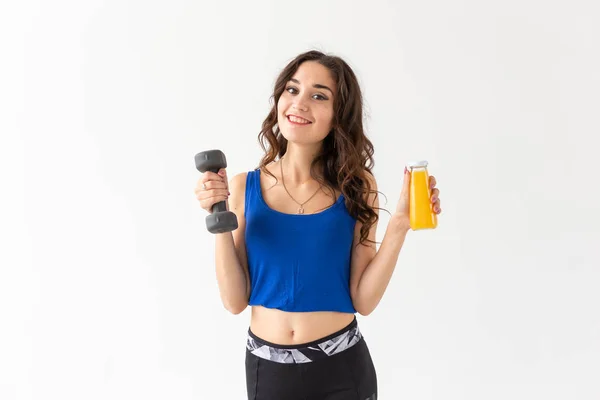 スポーツ、健康なライフ スタイル、人コンセプト - 彼女の手、別の手で白い背景の上にジュースの瓶にダンベルを持つ若い女性 — ストック写真