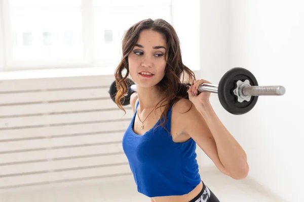 Fitness, deporte y el concepto de la gente - sonriente mujer deportiva con barra haciendo sentadilla dividida o embestida — Foto de Stock