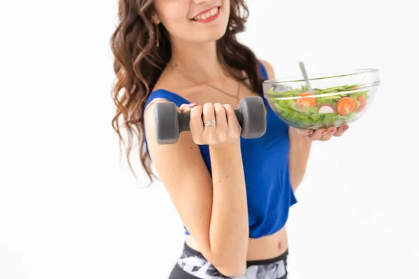 Esporte, estilo de vida são, conceito de pessoas - fim de mulher morena jovem com salada e um halteres. Ela está sorrindo e desfrutando do estilo de vida saudável — Fotografia de Stock