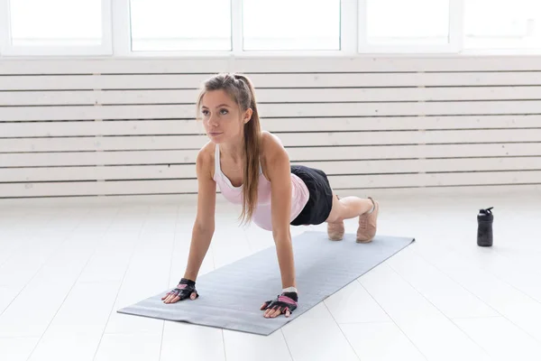 Estilo de vida saludable, deporte, concepto de personas: una mujer joven está haciendo ejercicio en el gimnasio o en casa. Ella está presionando en el traje deportivo — Foto de Stock