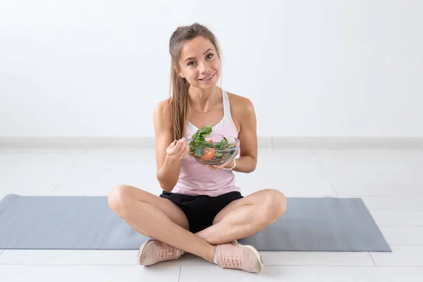 Estilo de vida saludable, personas y concepto deportivo - Mujer de yoga con un tazón de ensalada de verduras después de entrenar sobre fondo blanco —  Fotos de Stock