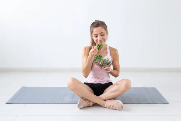 Estilo de vida saludable, personas y concepto deportivo - Mujer de yoga con un tazón de ensalada de verduras después de entrenar sobre fondo blanco —  Fotos de Stock