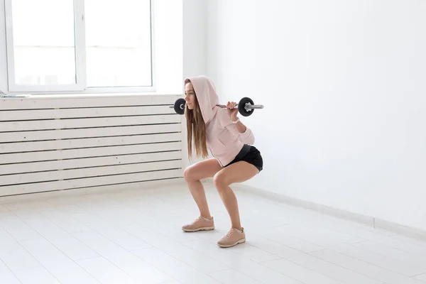 Esporte, fitness e conceito de pessoas - Bela jovem mulher exercitando agachamento com barra — Fotografia de Stock