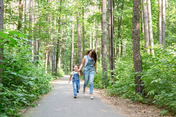 Концепция семьи, природы и людей - Мать и милая маленькая дочь проводят время вместе на прогулке в лесу — стоковое фото