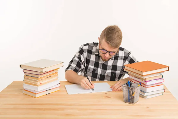 Concepto de personas, conocimiento y educación: el estudiante feliz se sienta a la mesa y toma notas en un cuaderno — Foto de Stock
