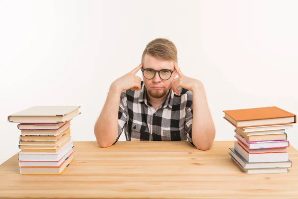 Persone, conoscenza e concetto di istruzione - Studente maschio stanco seduto a tavola con montagne di libri e non vuole studiare fino — Foto Stock