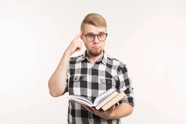 Examen, conocimiento y concepto de educación: el estudiante inteligente señala la cabeza o el cerebro sosteniendo libros en sus manos sobre un fondo blanco — Foto de Stock