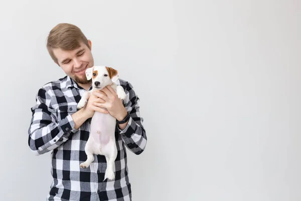 Mensen, huisdieren en dieren concept - jonge man die jack russell Terriër pup op witte achtergrond met kopie ruimte — Stockfoto