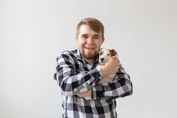 People, pet and dog concept - Smiling man over white background holding puppy Jack Russell Terrier