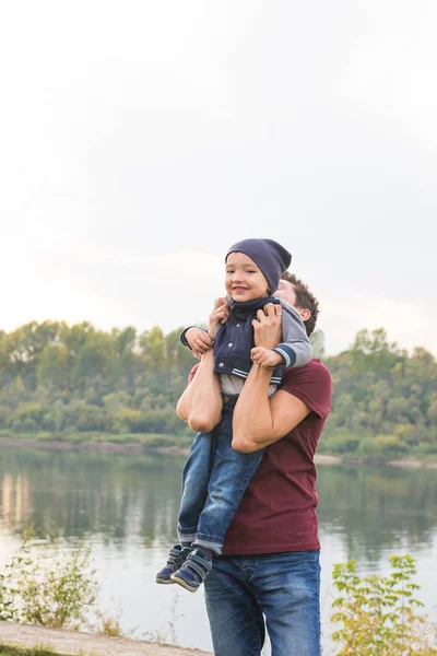 Infancia, concepto familiar - padre jugando con su hijo cerca del lago — Foto de Stock