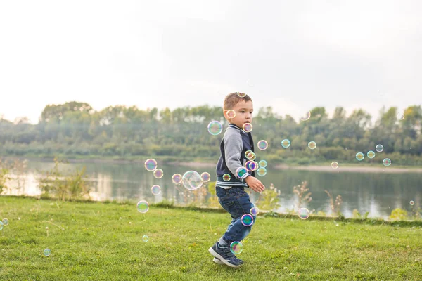 Infância, felicidade, conceito de pessoas - menino correndo pelas bolhas de sabão — Fotografia de Stock