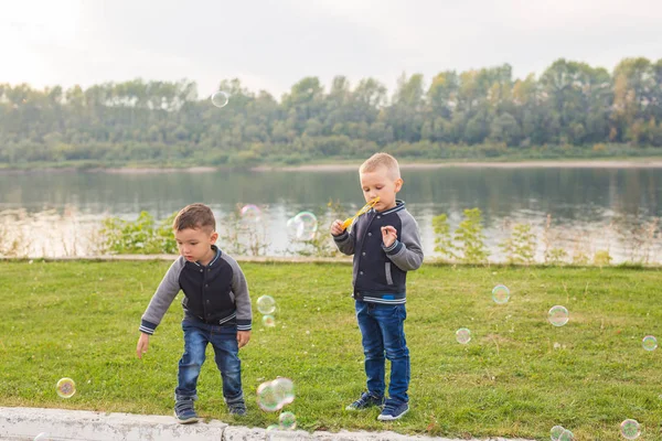 Children and childhood concept - Two brothers boys playing with colorful soap bubbles — Stock Photo, Image