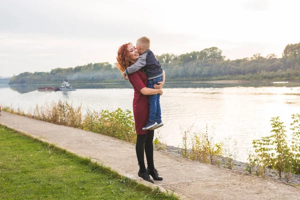 Familien- und Kinderkonzept - rothaarige Frau hält ihren Sohn über Wasser — Stockfoto