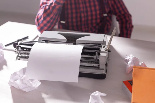 Día de los escritores y el concepto de la tecnología - Guapo escritor rodeado de trozos de papel centrado en el trabajo sobre fondo gris — Foto de Stock