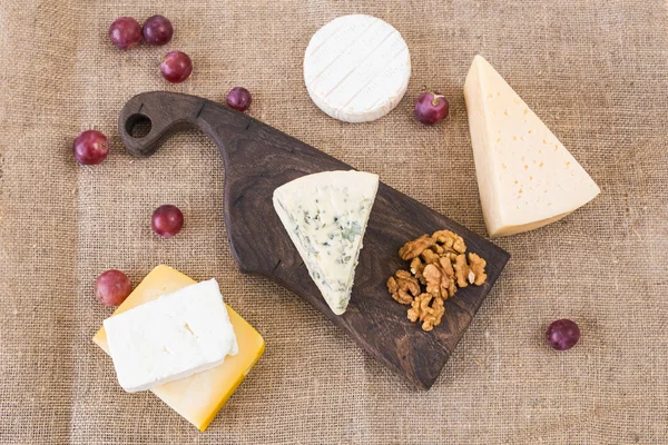 Fresh products. Cheese, brie, Camembert, grapes and nuts on rustic table.