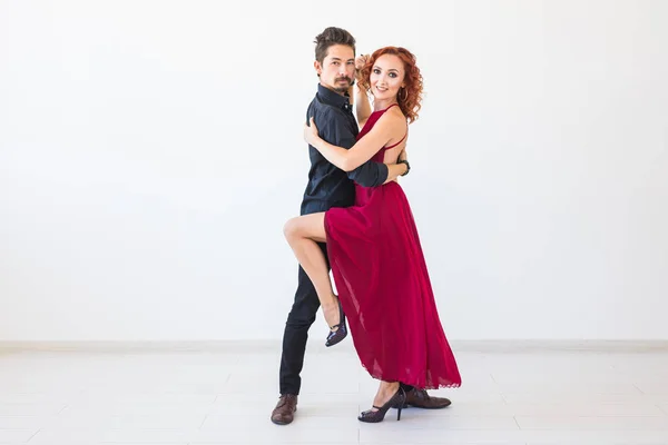 Dança social, bachata, kizomba, salsa, conceito de tango - Mulher vestida de vestido vermelho e homem em um traje preto sobre fundo branco com espaço de cópia — Fotografia de Stock