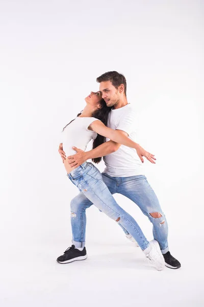 Pareja joven bailando baile social bachata, merengue, salsa, kizomba. Dos pose elegancia en habitación blanca . — Foto de Stock