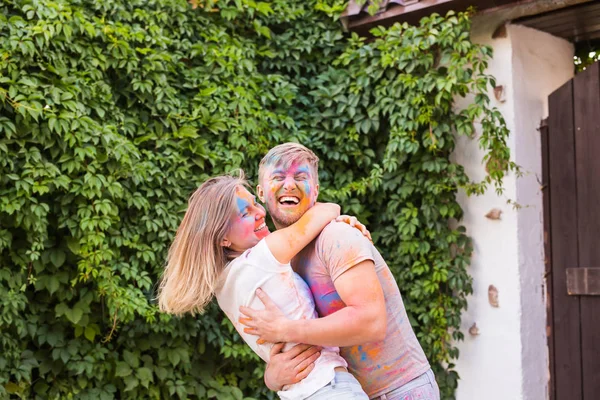 Amizade, festival de holi, conceito de pessoas - jovem casal brincando com cores no festival de holi — Fotografia de Stock