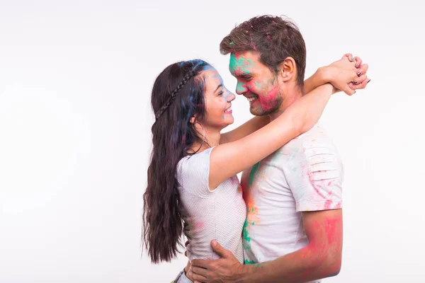 Amizade, amor, festival de holi, conceito de pessoas - jovem casal brincando com cores no festival de holi no fundo branco — Fotografia de Stock