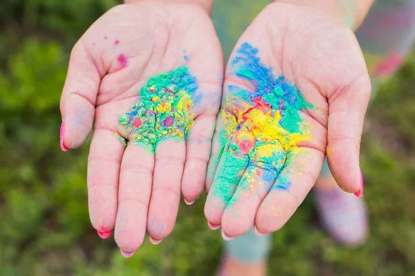 Holiday, festival holi and family concept - Palms of young people covered in different colors over nature background — Stock Photo, Image