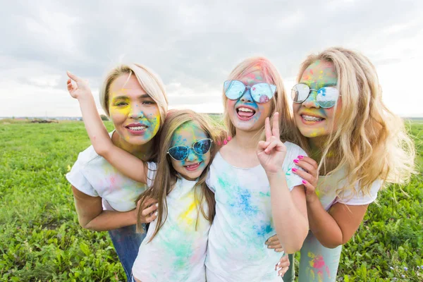 Amistad, vacaciones, concepto de color - amigos sonriendo y divirtiéndose en colores en el festival de holi —  Fotos de Stock