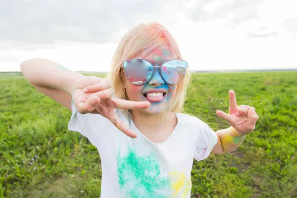 Los niños, el festival de holi y el concepto de vacaciones - niña feliz cubierto de polvo de color sonriendo sobre el fondo de la naturaleza — Foto de Stock