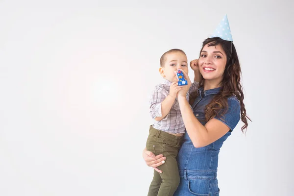 Personas, niños y concepto de vacaciones - Madre encantadora sostiene a su hijo con gorra de cumpleaños sobre fondo blanco con espacio para copiar — Foto de Stock