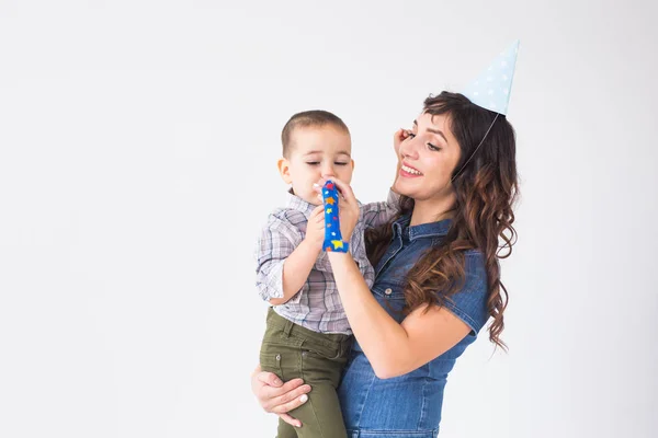 Personas, niños y concepto de vacaciones - Madre encantadora sostiene a su hijo con gorra de cumpleaños sobre fondo blanco — Foto de Stock
