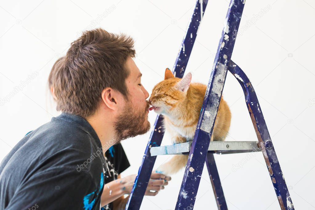 People, renovation, pet and repair concept - Portrait of funny guy with cat doing redecoration in apartment