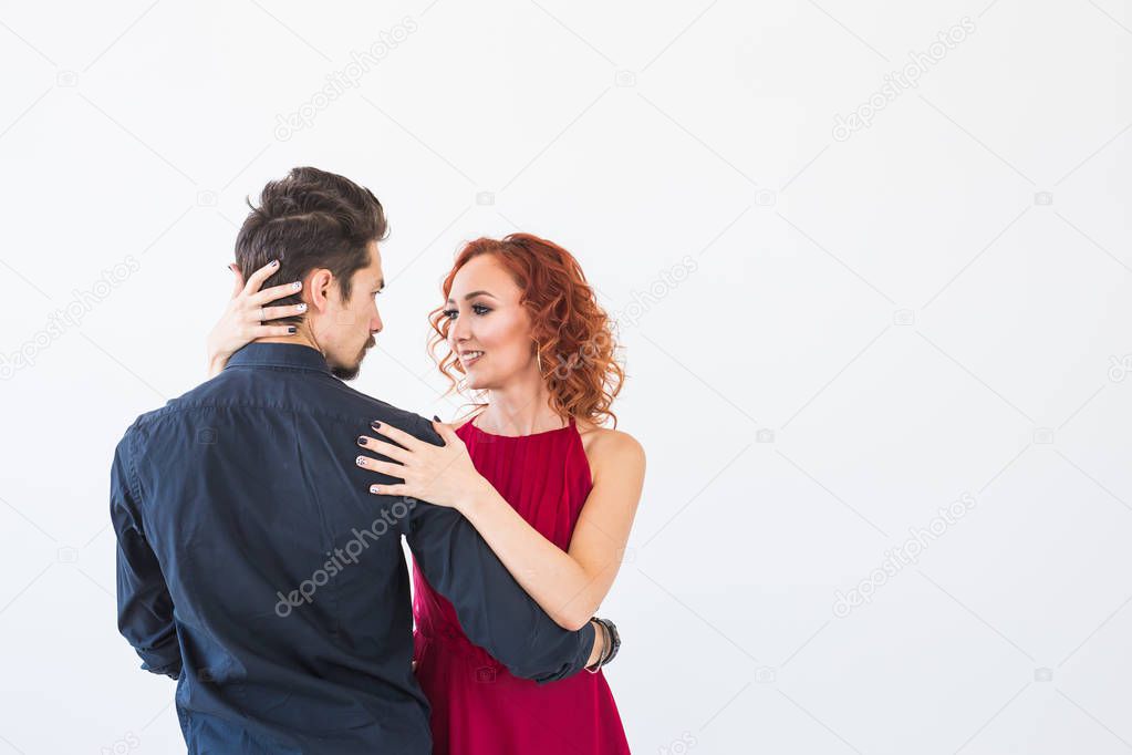 Romantic, social dance, people concept - couple dancing bachata in the studio, man hugging the woman from her back. Background with copy space
