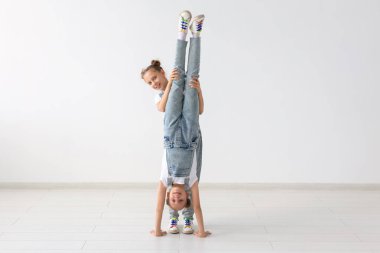 Aile ve spor kavram - iki acrobat ikiz kız ellerini beyaz arka plan üzerinde duruyorsun