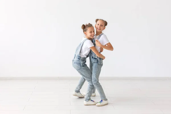 Concetto di famiglia e amore - due sorridenti sorelle gemelle che si abbracciano su sfondo bianco — Foto Stock