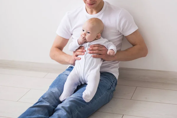 Crianças, conceito de família e paternidade - pai careca feliz segurando a filha bebê infantil de joelhos no fundo branco — Fotografia de Stock