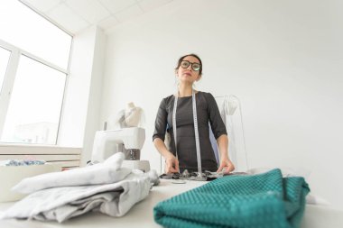 Terzi, moda tasarımcısı, terzi ve insanlar kavramı - iş yerinde bir kadın terzi portresi
