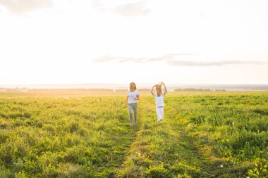 Aile, yaz ve tatil kavramı - yeşil alanında çalışan kızı elini tutan anne