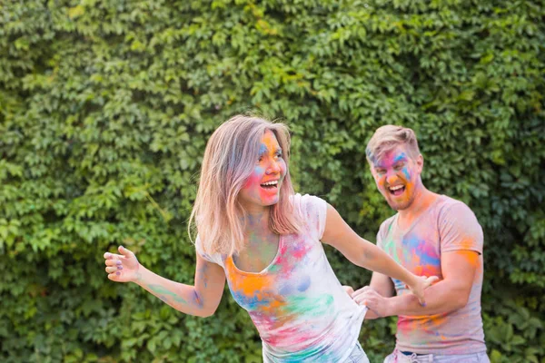 Amizade, festival de holi, conceito de pessoas - jovem casal brincando com cores no festival de holi — Fotografia de Stock