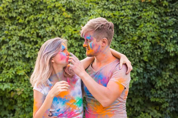 Концепция праздников, холи и людей - счастливая пара веселится с разноцветным порошком на лицах — стоковое фото