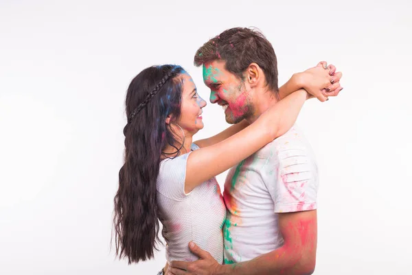 Vacances, holi et concept de personnes - Couple heureux s'amuser avec de la poudre multicolore sur leurs visages sur fond blanc — Photo