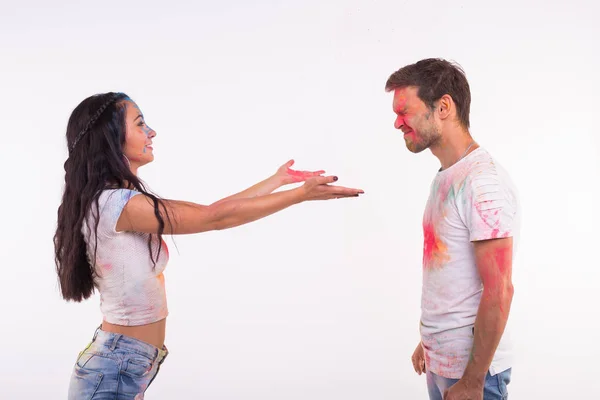 Conceito de férias, holi e pessoas - Casal feliz se divertindo com pó multicolorido em seus rostos no fundo branco — Fotografia de Stock