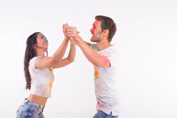 Férias, dança social, holi e conceito de pessoas - casal feliz se divertindo e bachata dança ou kizomba com pó multicolorido em seus rostos em fundo branco — Fotografia de Stock