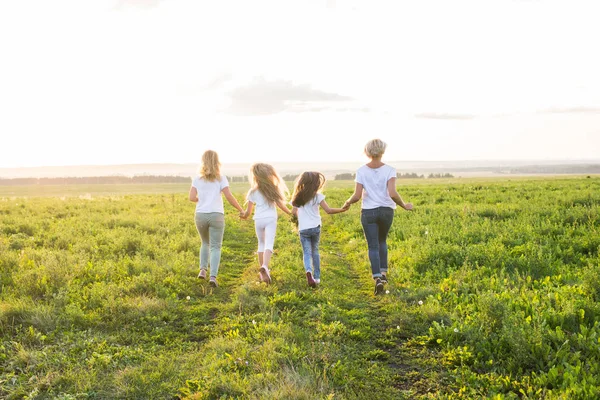 Концепция семьи, лета и отпуска - Группа женщин и девочек, отправляющихся в путь в зеленом поле — стоковое фото