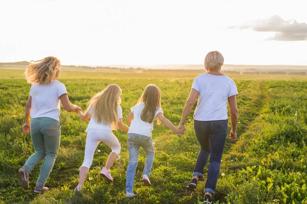 Familie, de zomer en de vakantie concept - groep voor vrouwen en meisjes weggaat in groene veld — Stockfoto